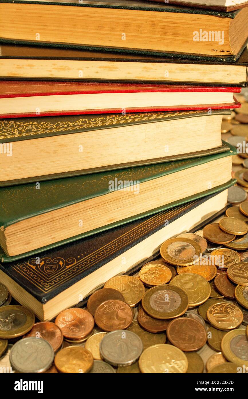 Pile of classics books surrounded with coins. The currency of the money is Brazilian Real Stock Photo