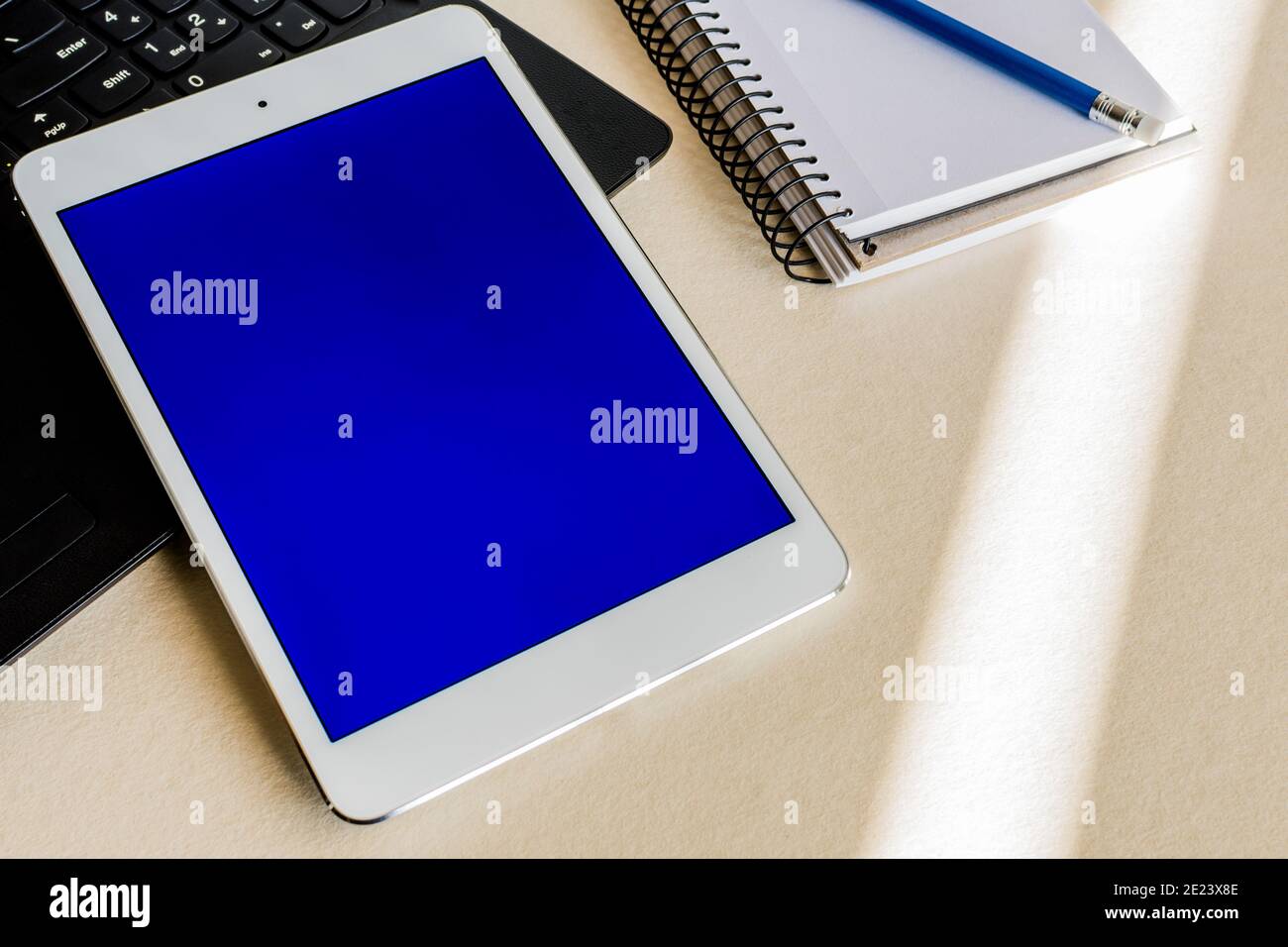 Tablet with blue screen on the keyboard of a laptop on a desk - technology and business concept Stock Photo