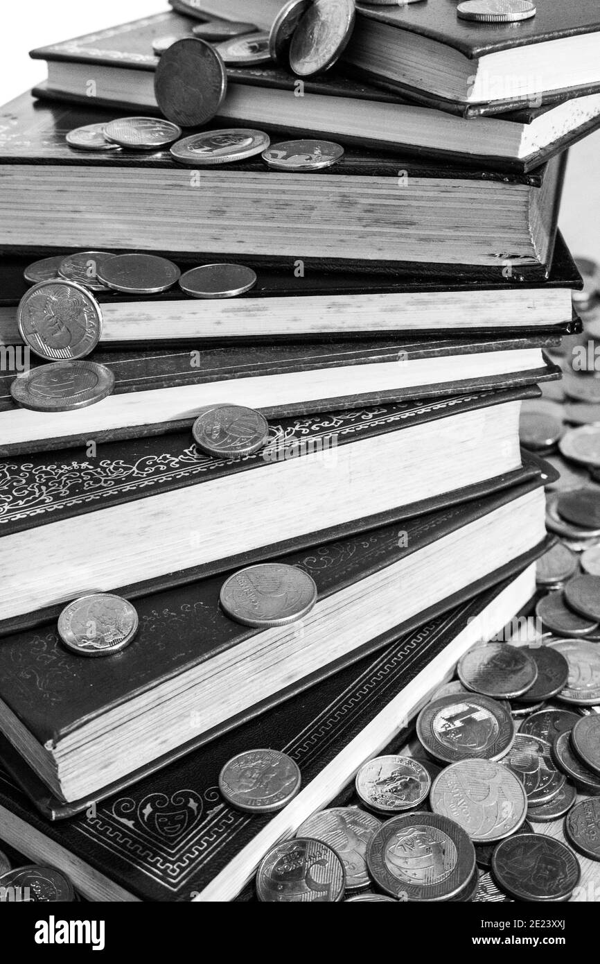 Pile of books surrounded by many different coins [Black and White version] Stock Photo