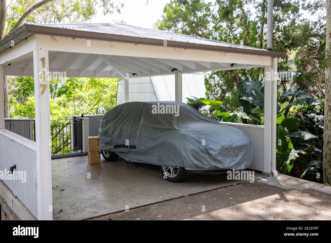 Australian car under a carport in Sydney also covered with protective grey cover sheet to prevent dust and damage,Sydney,Australia Stock Photo