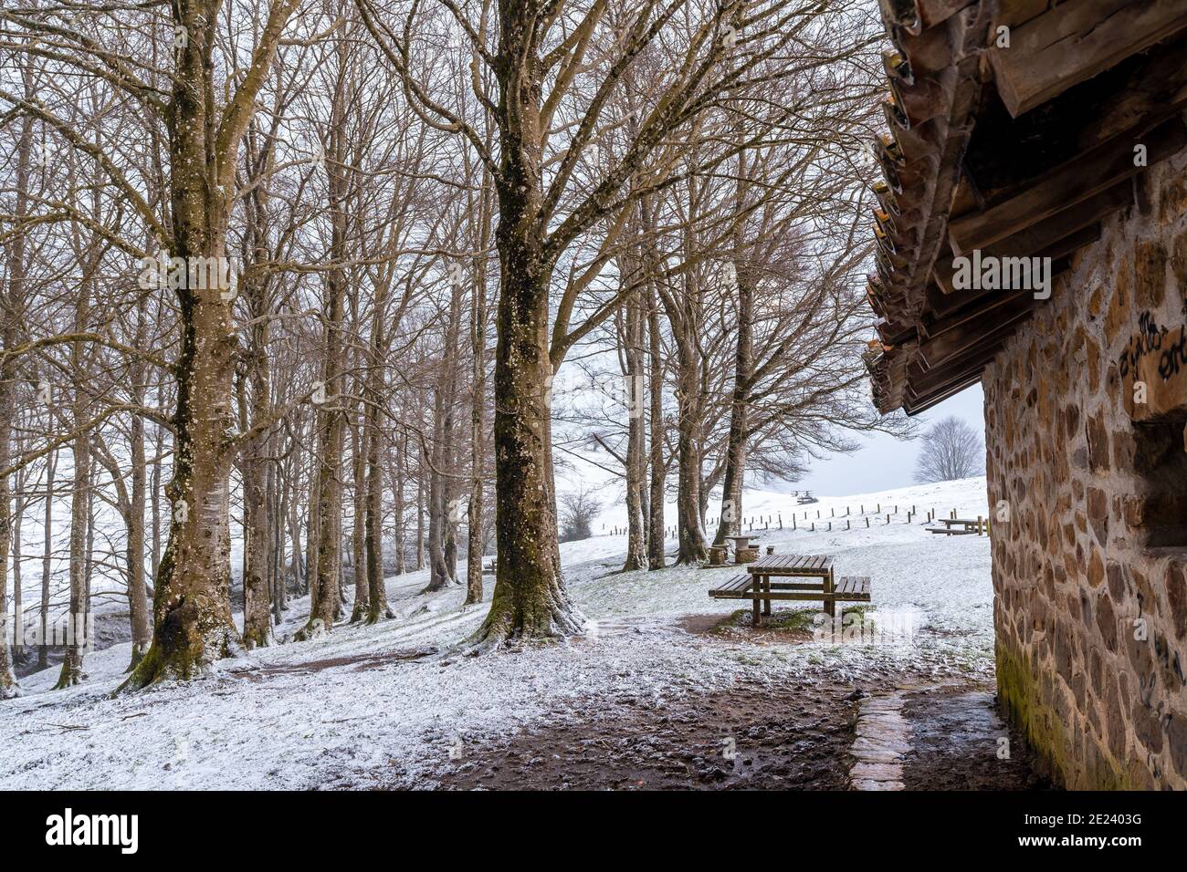 Snow covered area with picnic benches seen through a stone building ...