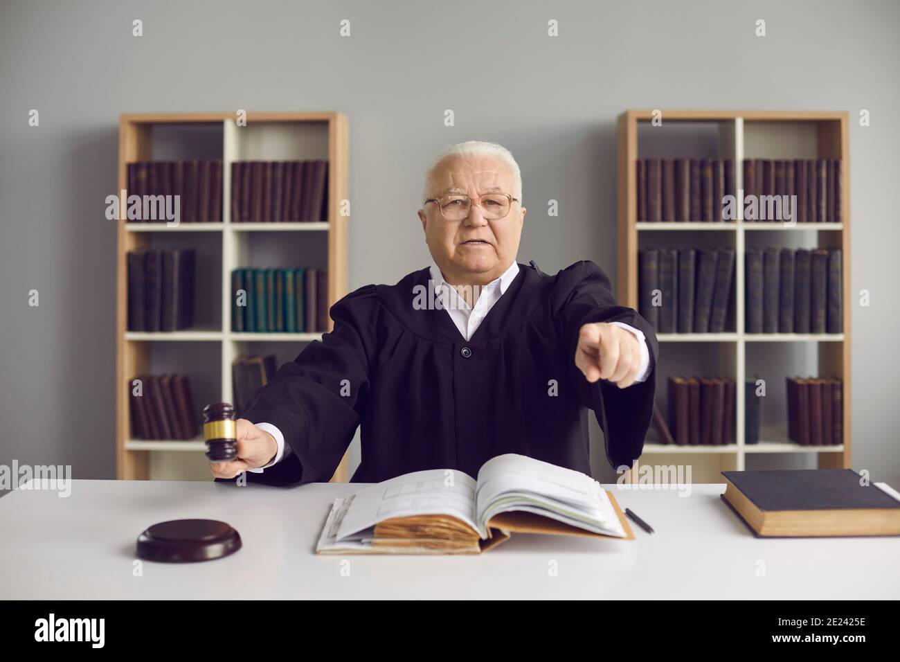 Judge holding gavel, pointing at camera and pronouncing sentence in court hearing Stock Photo