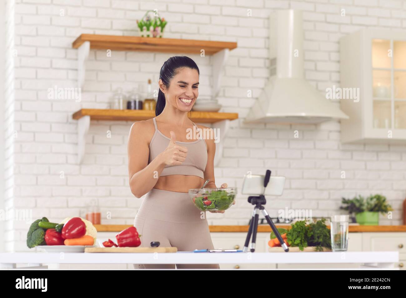 Smiling fit vlogger filming culinary video blog, giving dieting advice and sharing salad recipe Stock Photo