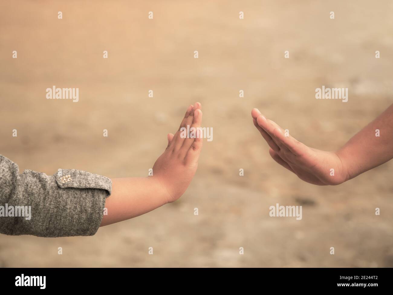Selective focus shot of two young children's hands reaching out to touch each other Stock Photo