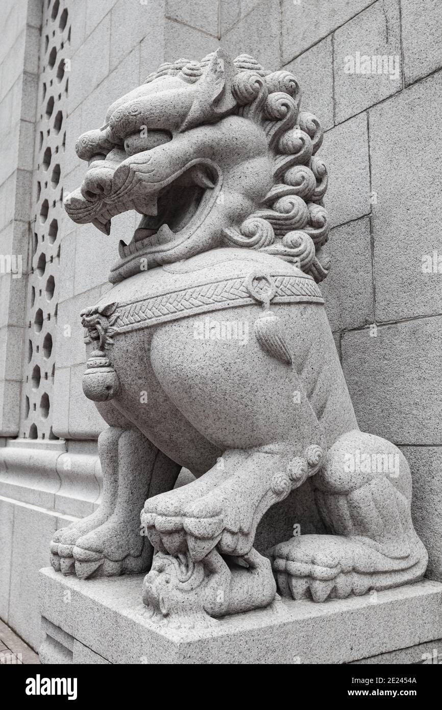 Traditional white stone Chinese lion statue at the entrance to Buddhist temple in Hong Kong city Stock Photo