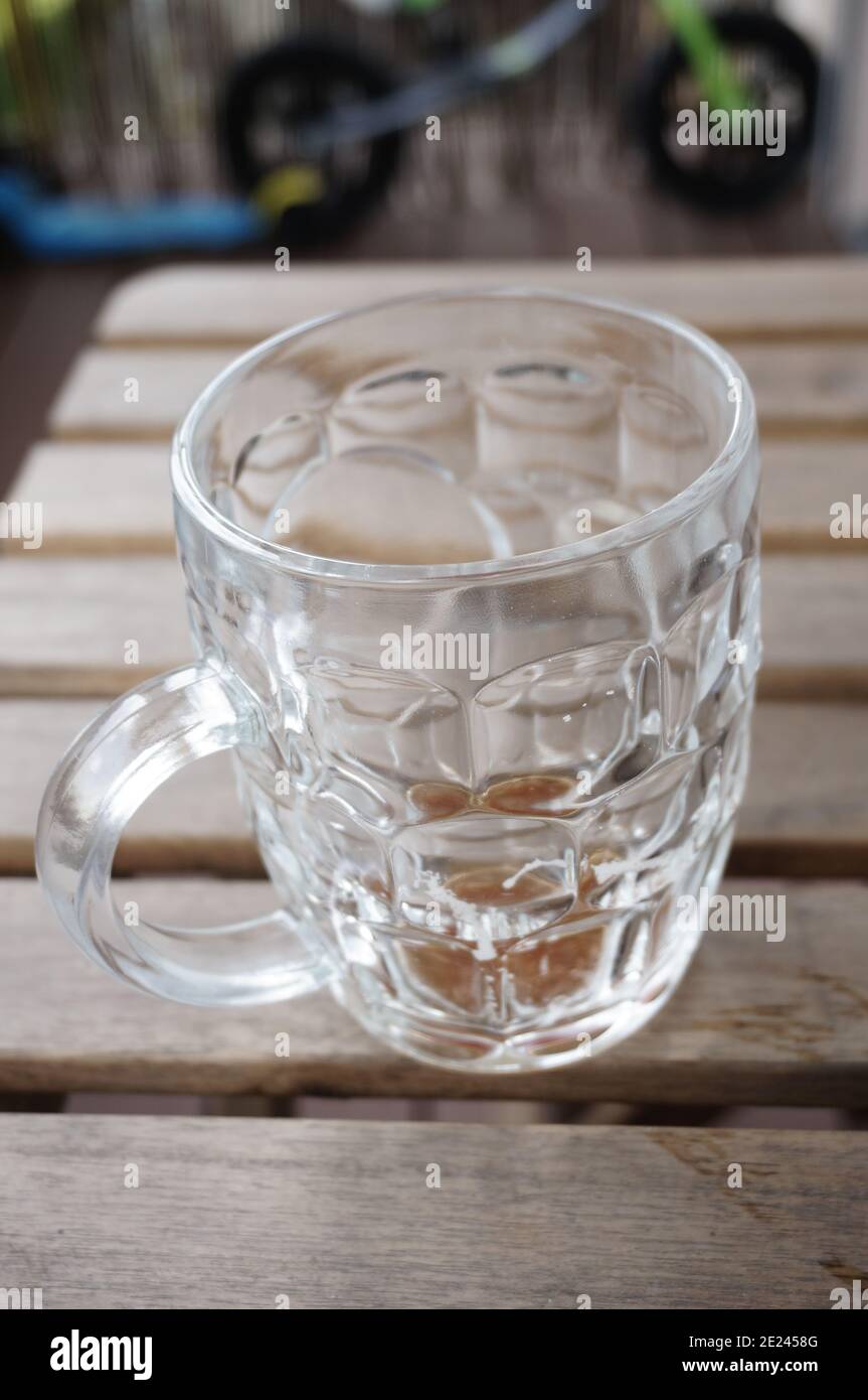 Vertical shallow focus shot of a glass mug on the wooden tabl Stock Photo