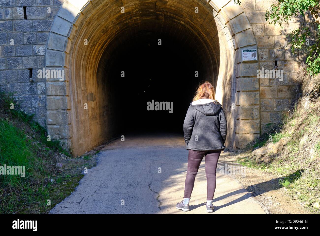 Back view of a girl looking into the dark tunnel Stock Photo