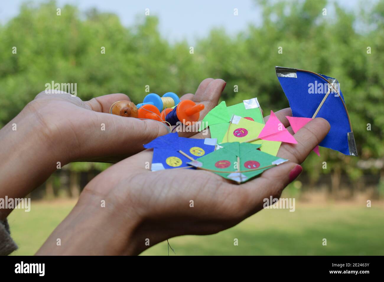 selective focus of miniature spools and kites, thread rolls called as Manjha or maanja in hand palms. Toy spools manja on the occasion of kite flying Stock Photo