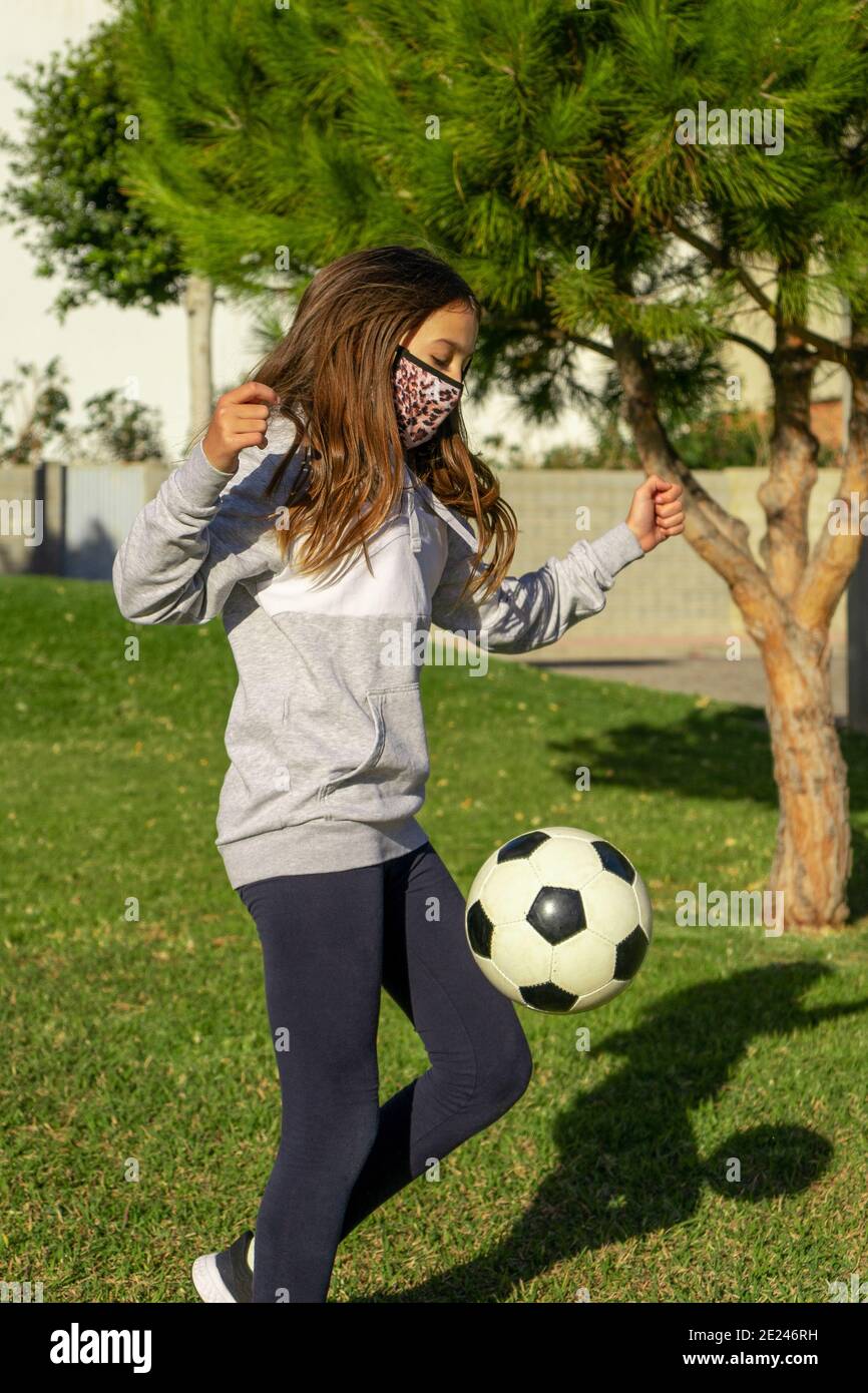 Beautiful little girl playing soccer in a nice park with natural grass ...