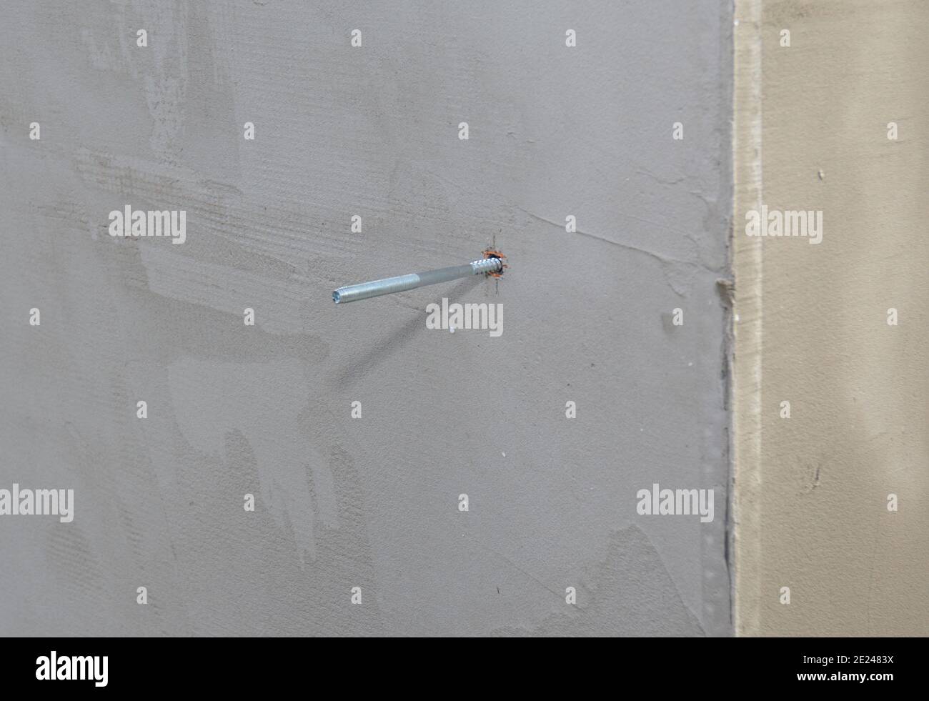 A metal screw anchor, bolt anchor, metal fastener, screwed in a concrete wall with an outside