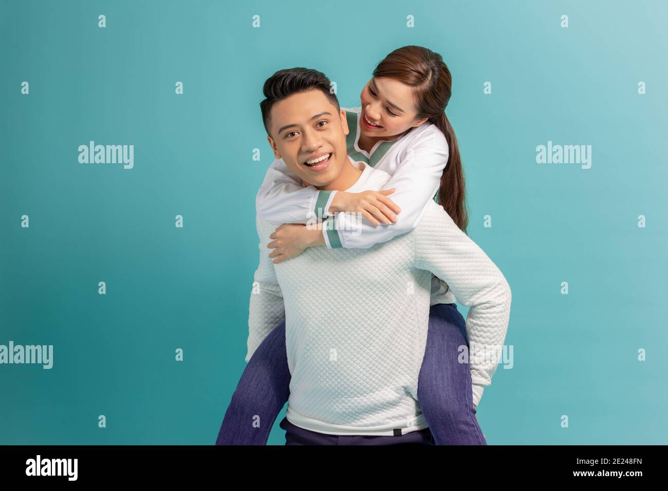 Spending great time together. Happy young man carrying his beautiful girlfriend on shoulders and smiling while standing Stock Photo