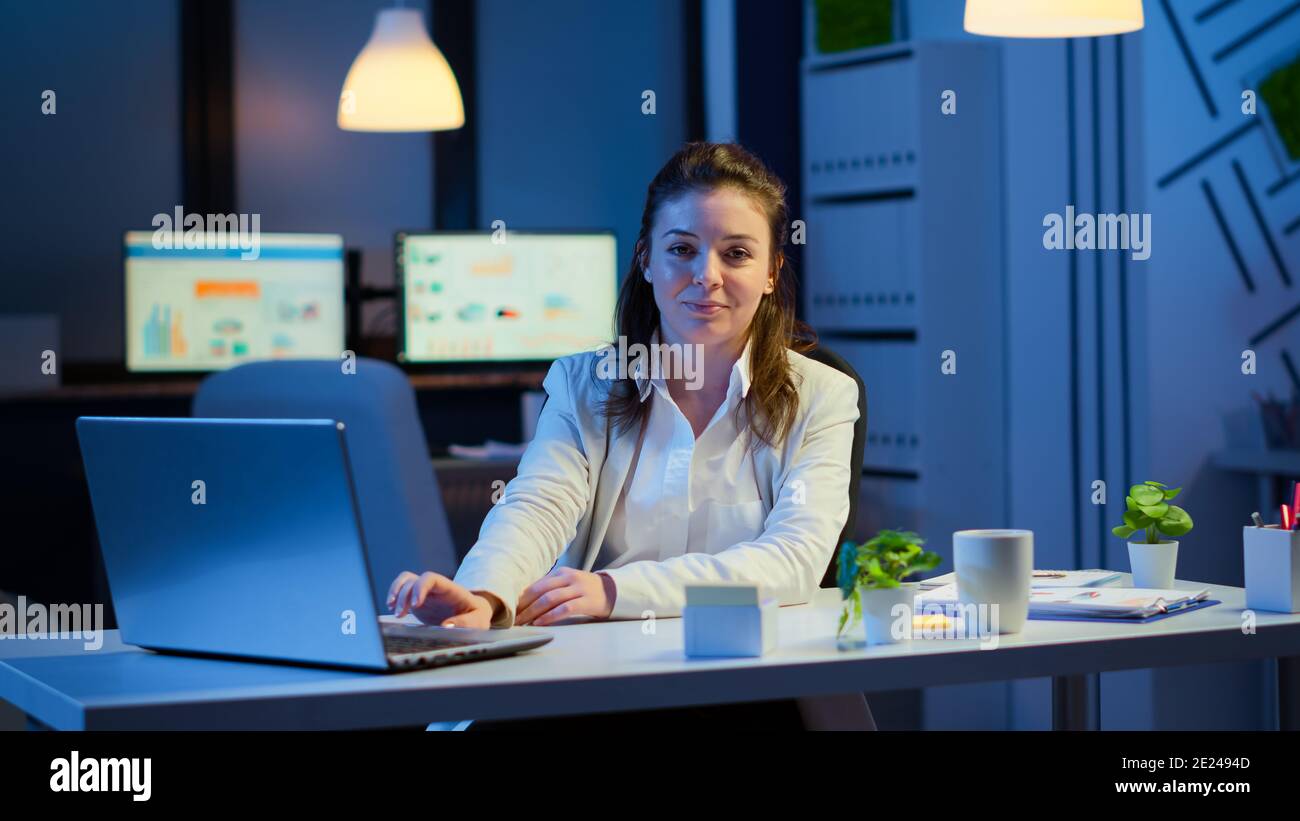 Staff Using Technology Business woman looking at camera smiling after typing on laptop sitting ...