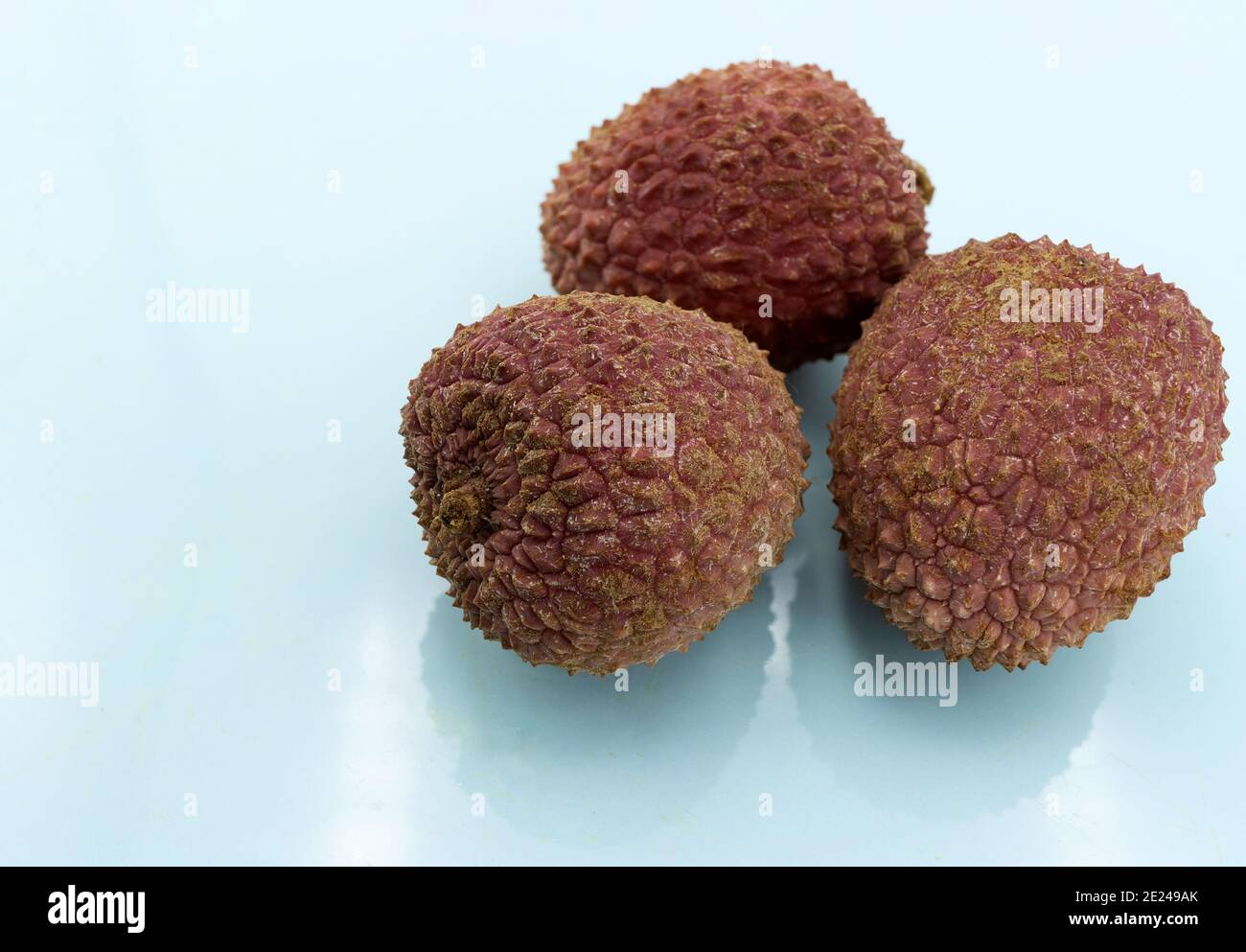 Three lychees isolated on bluish background Stock Photo