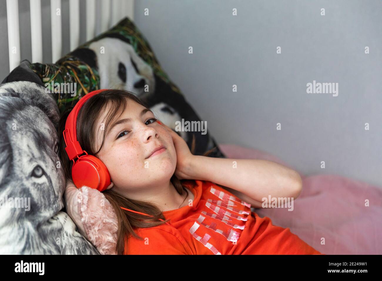 Girl with on bed wearing headphones Stock Photo Alamy