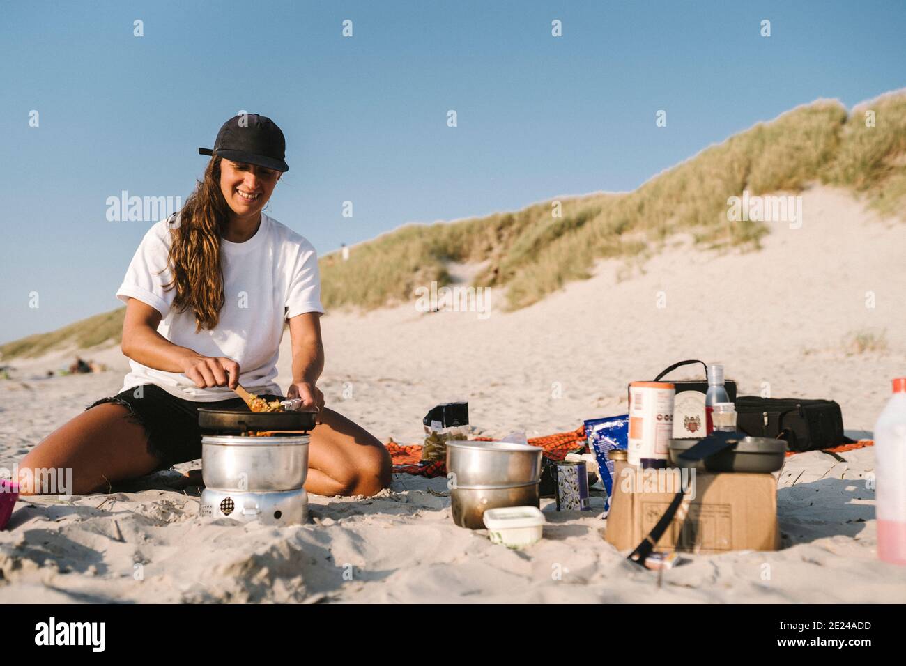 Smiling woman cooking on beach Stock Photo