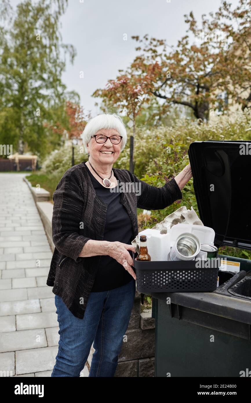 Smiling senior woman carrying recycling rubbish Stock Photo