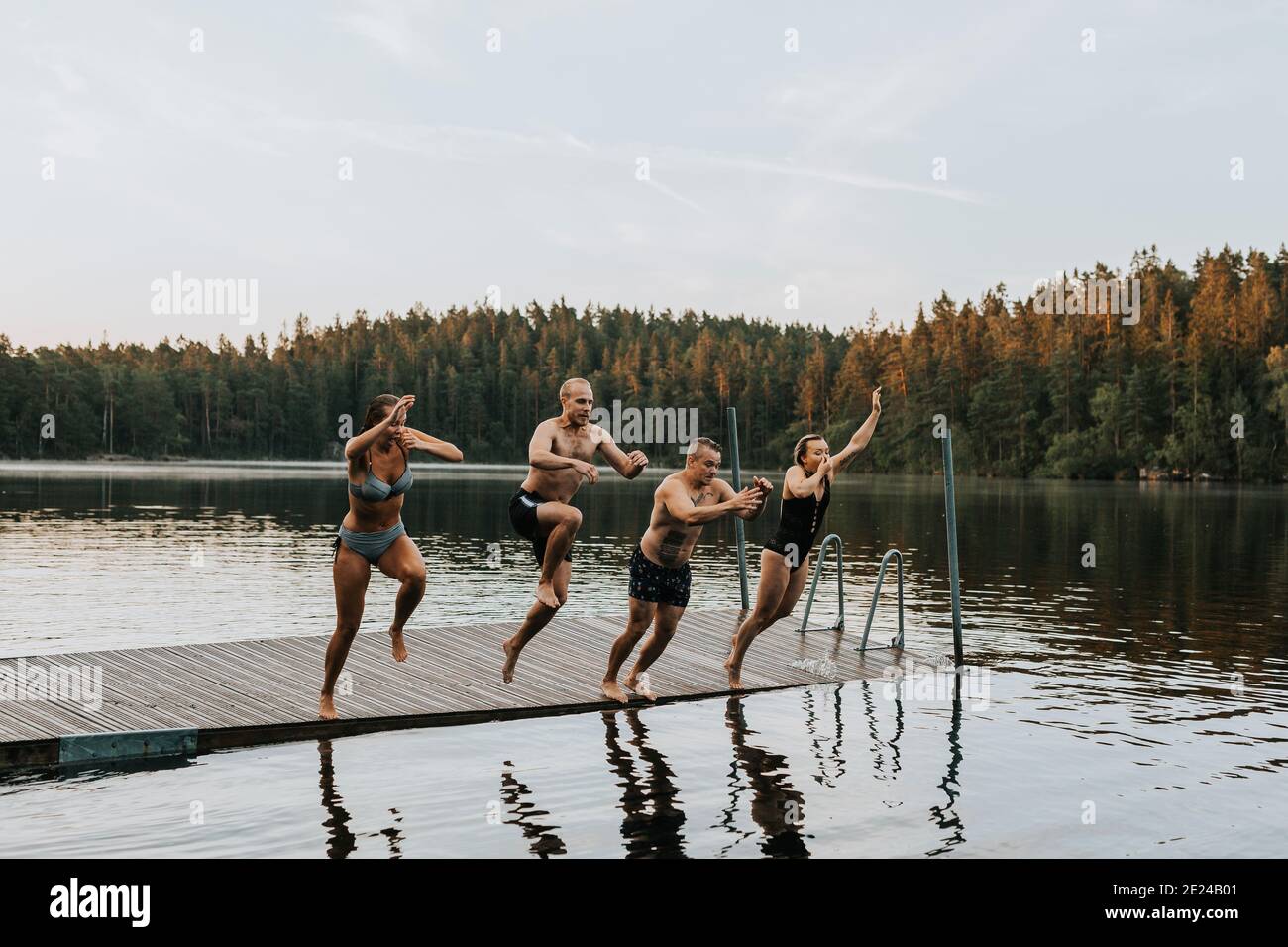 Friends jumping into lake Stock Photo