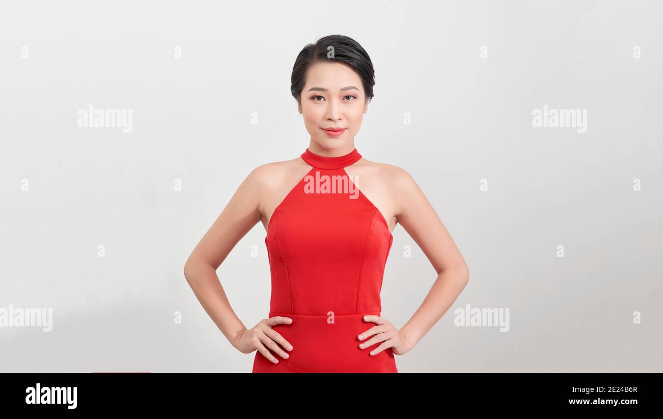 Portrait of a cheerful young asian woman in red dress posing and ...