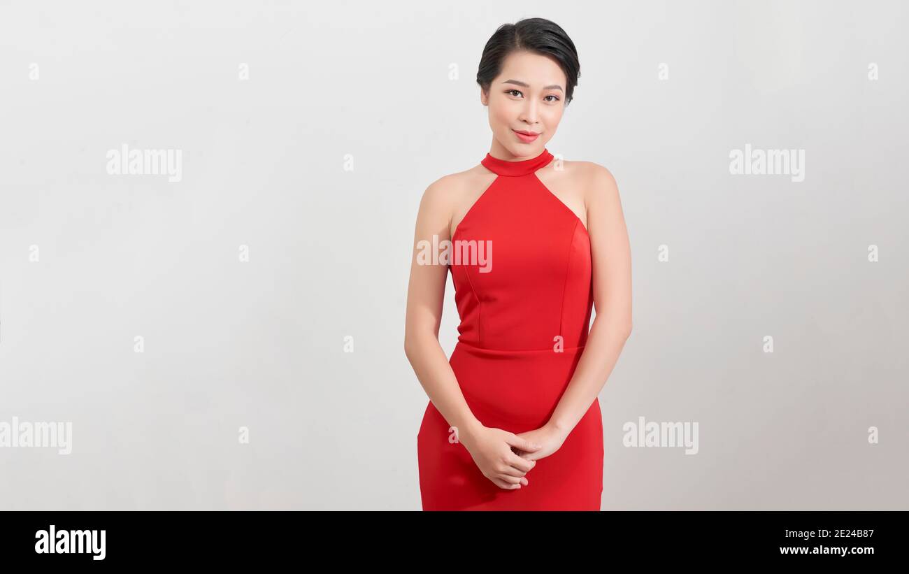 Portrait of a cheerful young asian woman in red dress posing and ...