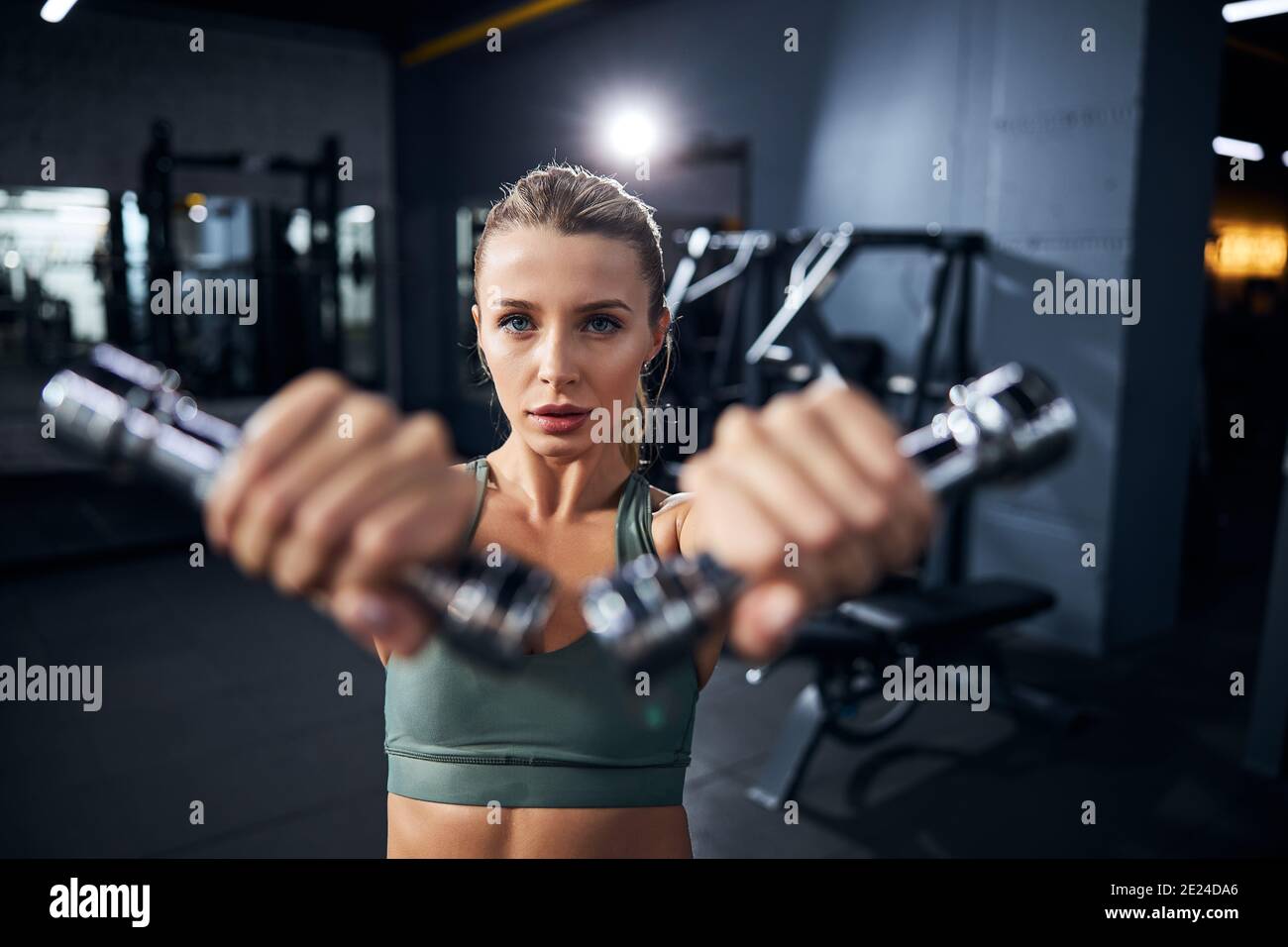 Female athlete is performing dumbbell front raises Stock Photo - Alamy