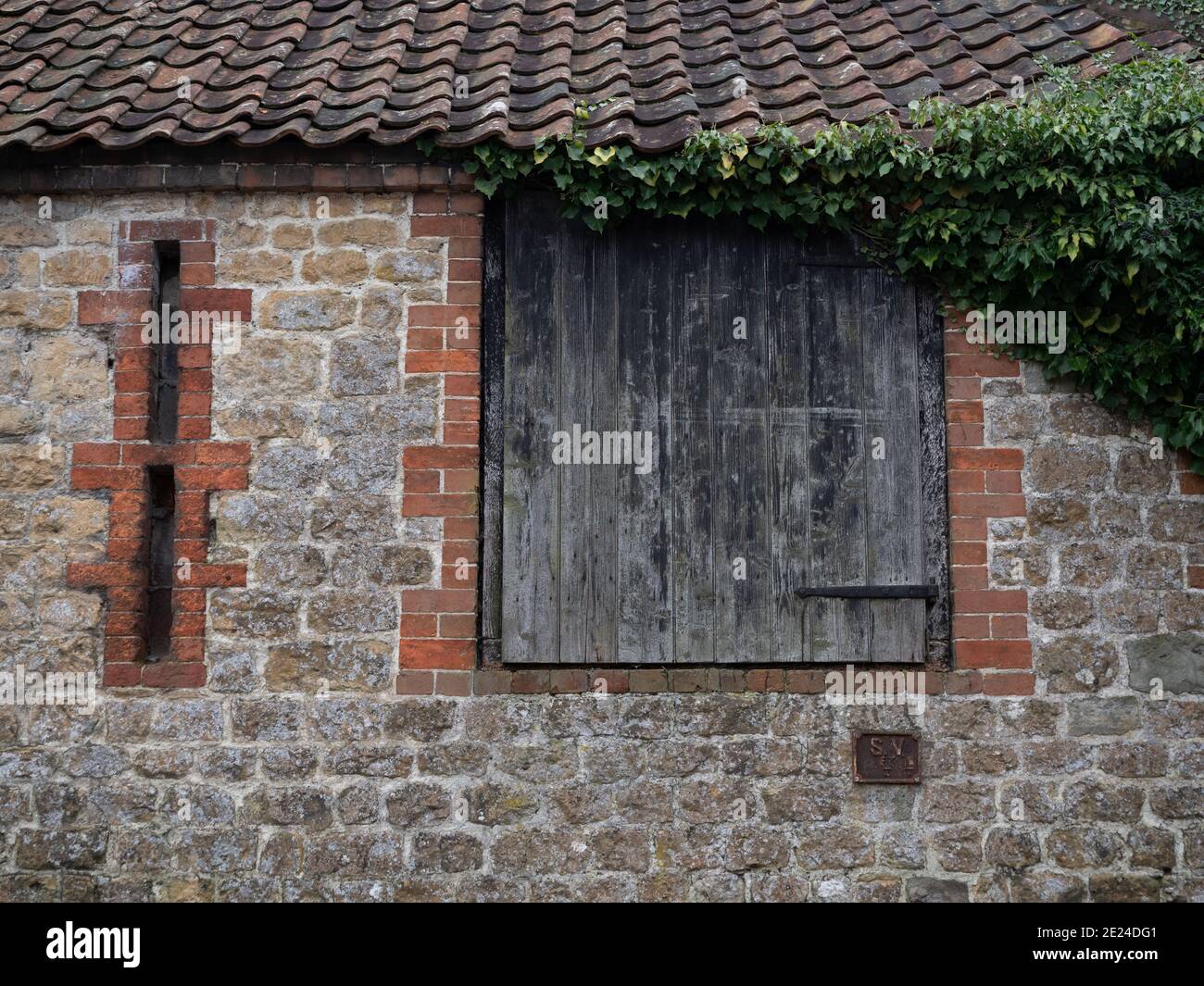 Elevated barn door with 'arrow slits' on old stone barn at Westbury Leigh, Wiltshire, England, UK. Stock Photo