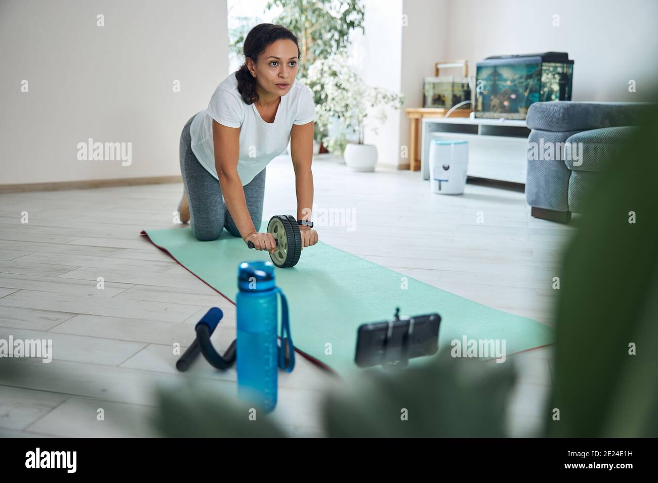 Fitness vlogger doing the kneeling ab wheel rollout Stock Photo