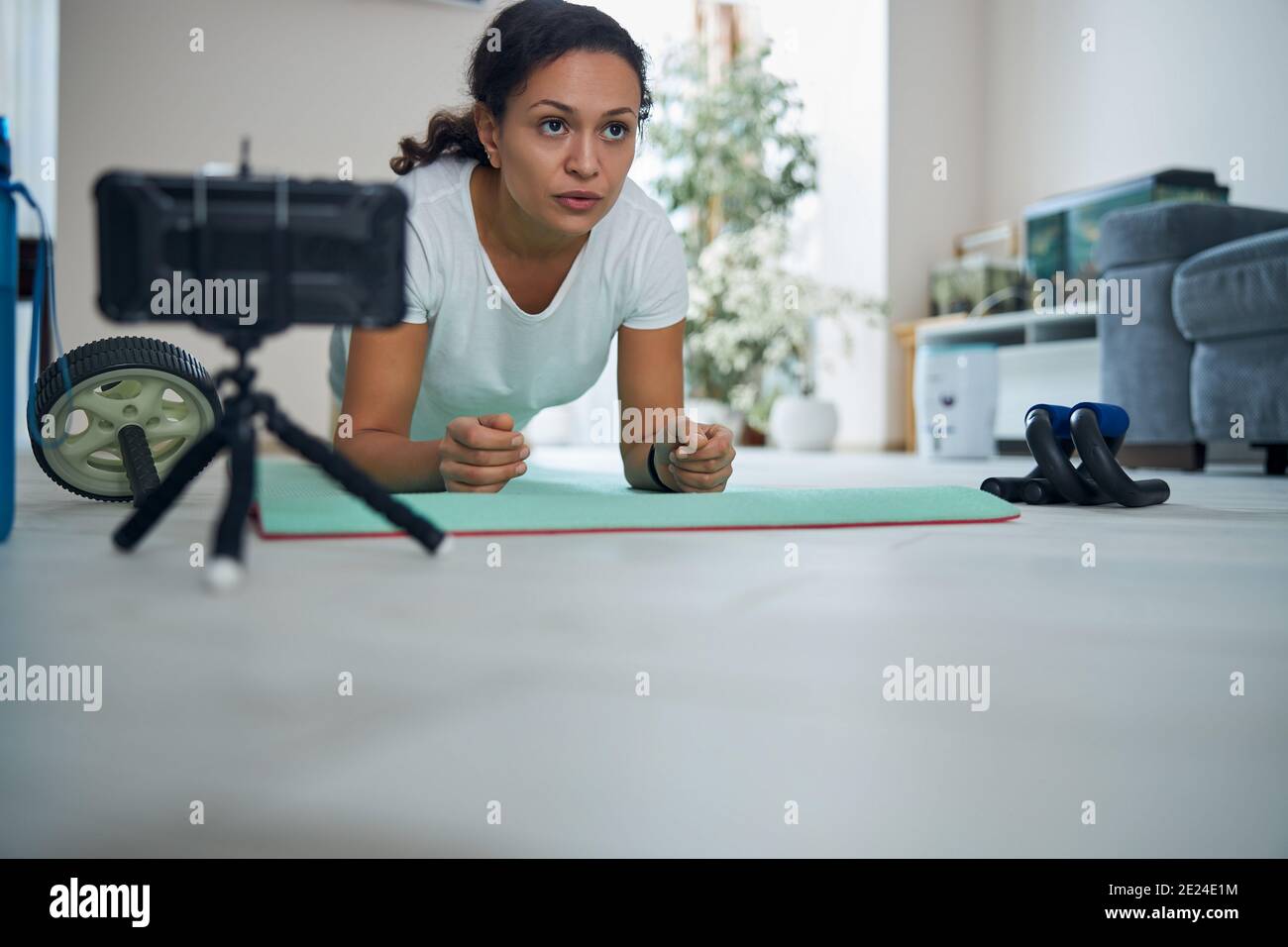 Serious dark-haired vlogger performing the core-strengthening exercise Stock Photo