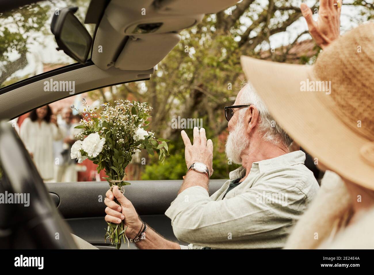 Man waving while sitting in convertible car Stock Photo