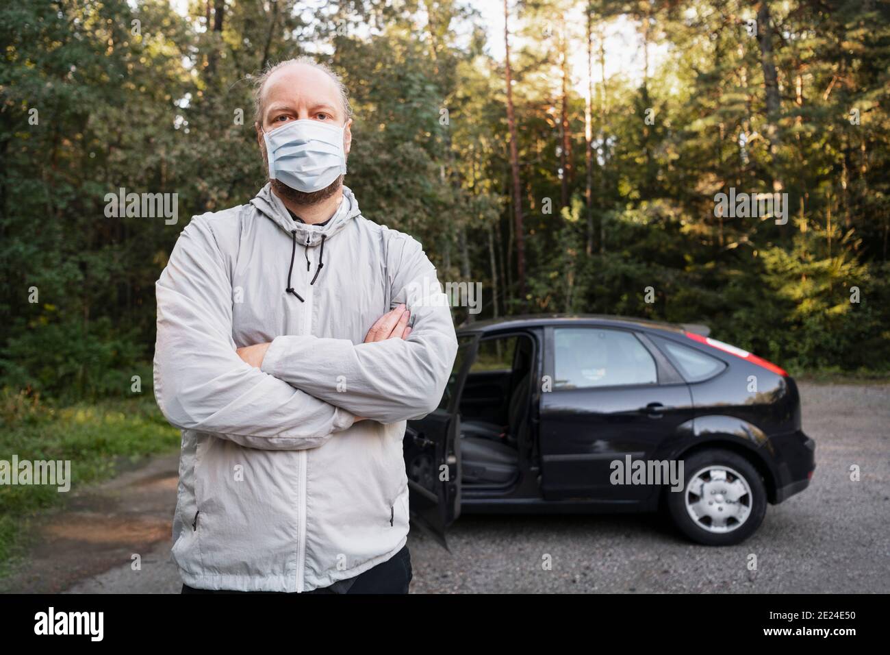 Man wearing face mask, parked car on background Stock Photo