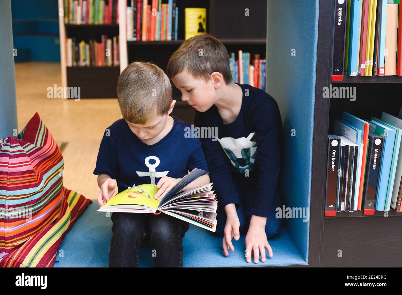 Boys looking at book in library Stock Photo