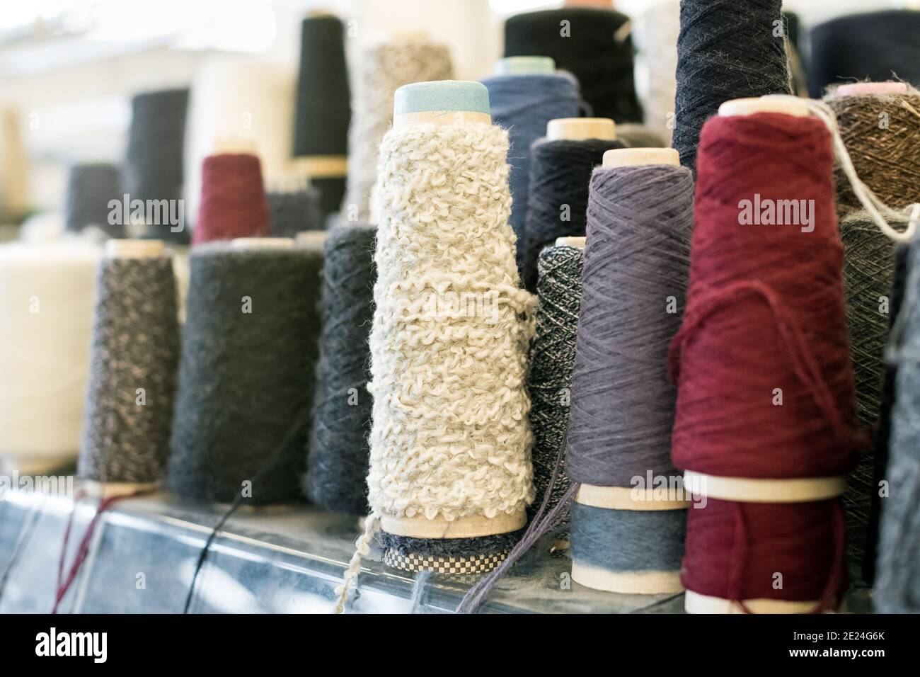 Spools and reels of spun cashmere wool or yarn in assorted colors and textures on a shelf in close up Stock Photo