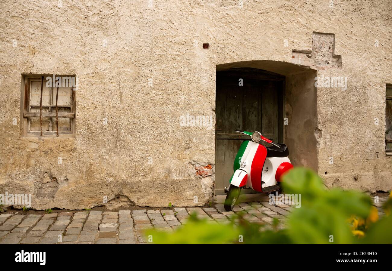 Vintage motorbike in italian flag colors parked near old rustic wall. Inspiring atmospheric spirit of Italy. Large textured foreground on left side of Stock Photo