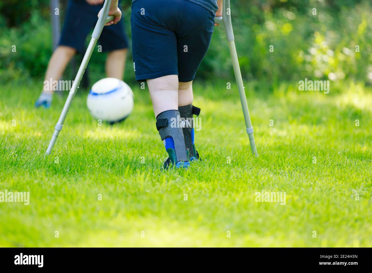 Low section of child using crutches playing football Stock Photo