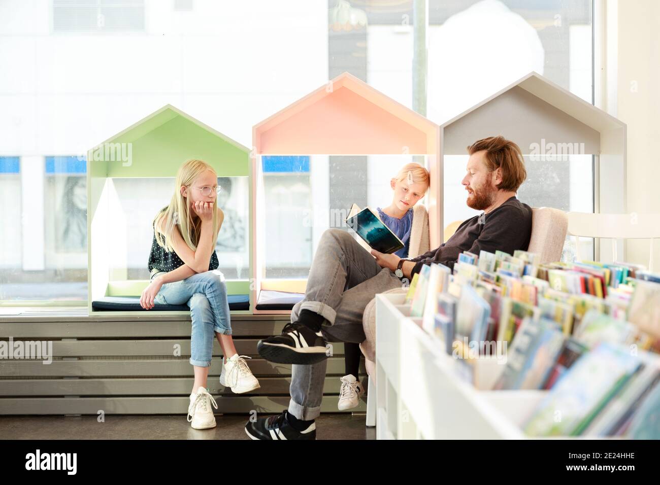 Father reading daughters book in library Stock Photo