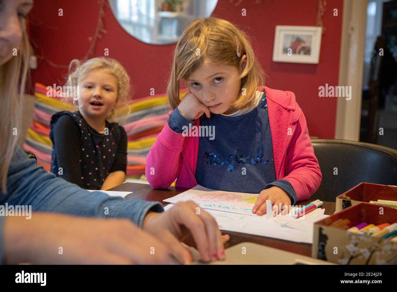 Girls of 3 and 5 years old doing school work with their mum at home during the Covid school closure. Stock Photo
