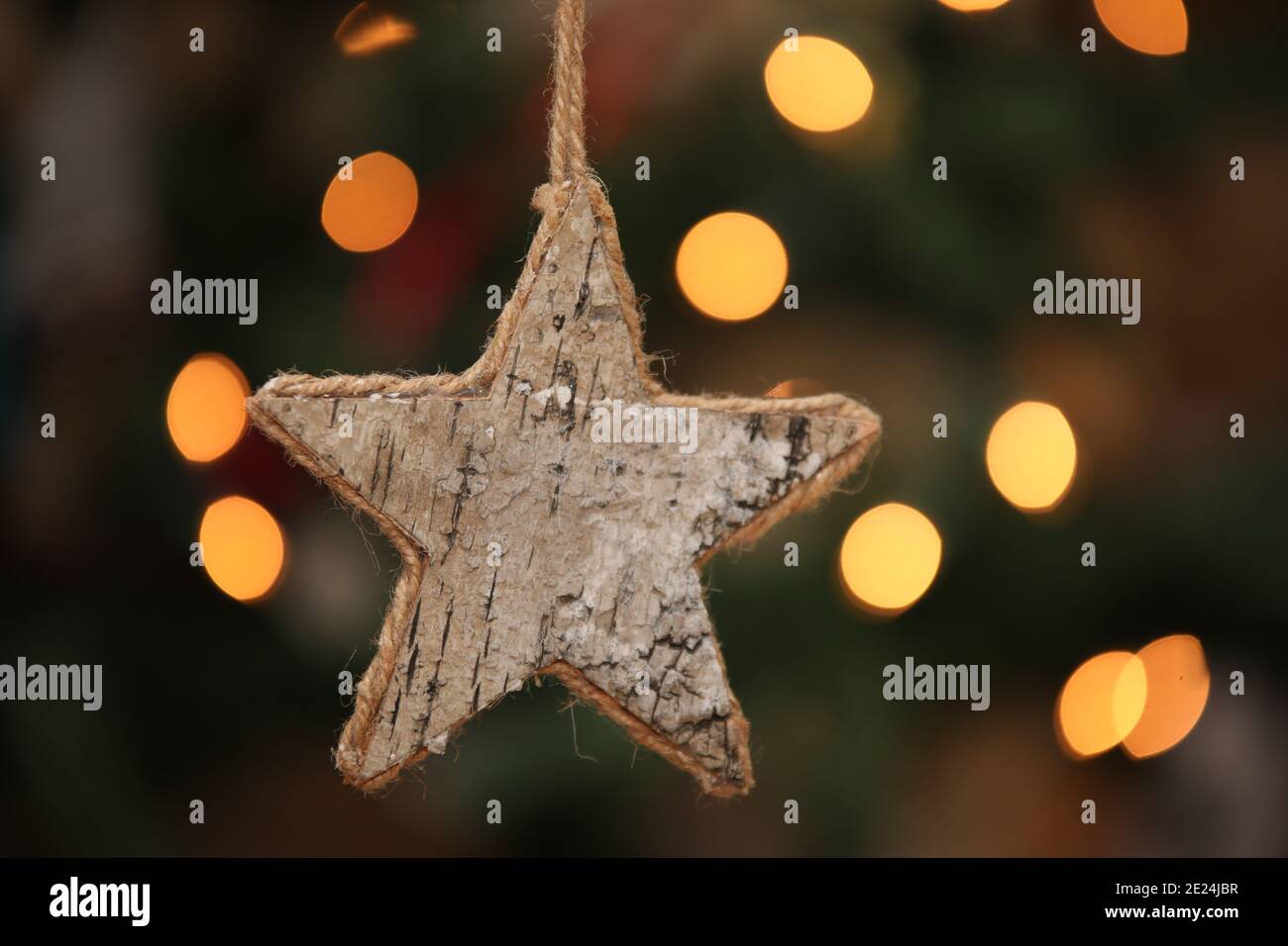 Handmade star-shaped ornament with a Christmas tree in the background Stock Photo