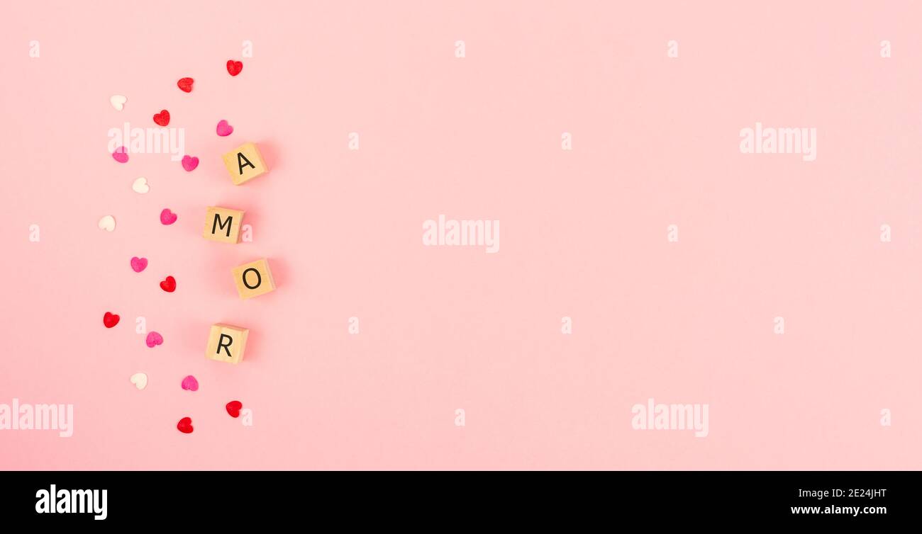 Word AMOR on wooden cubes and hearts on a pink background. Copy space. sob Stock Photo