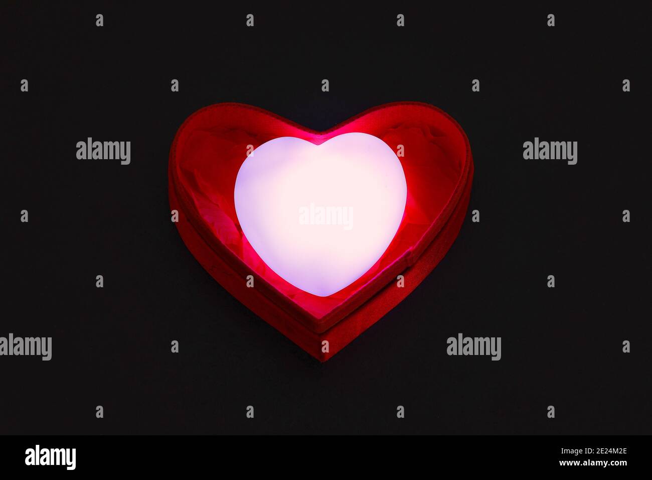 Selective focus of Beautiful valentines day background.  Heart-shaped red gift box with a glowing heart inside on Black Background, top view. Stock Photo
