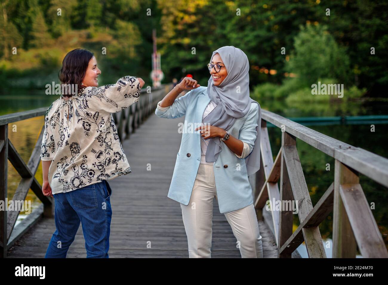 Female friends using elbow greeting Stock Photo