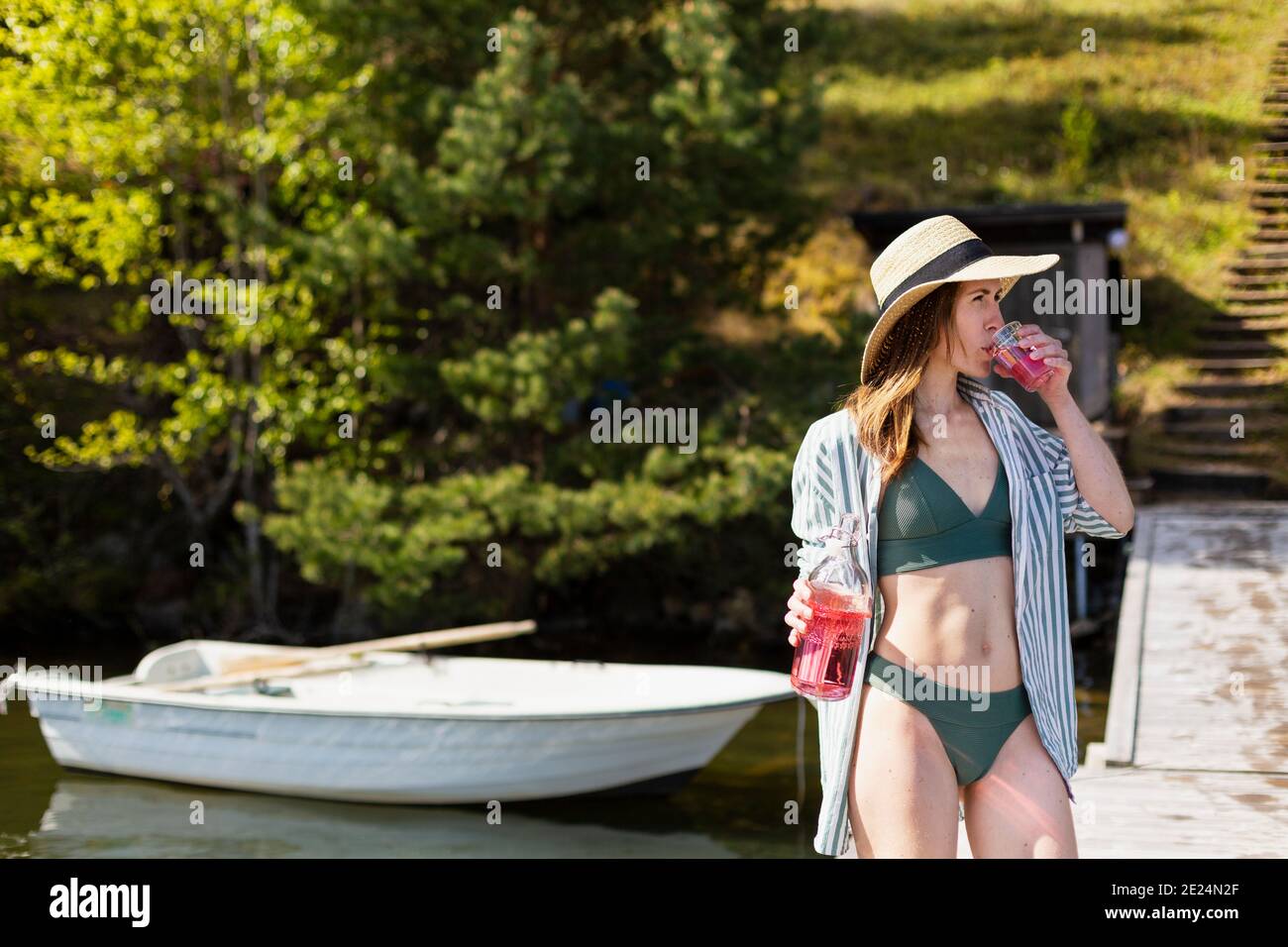 Woman having drink on jetty Stock Photo