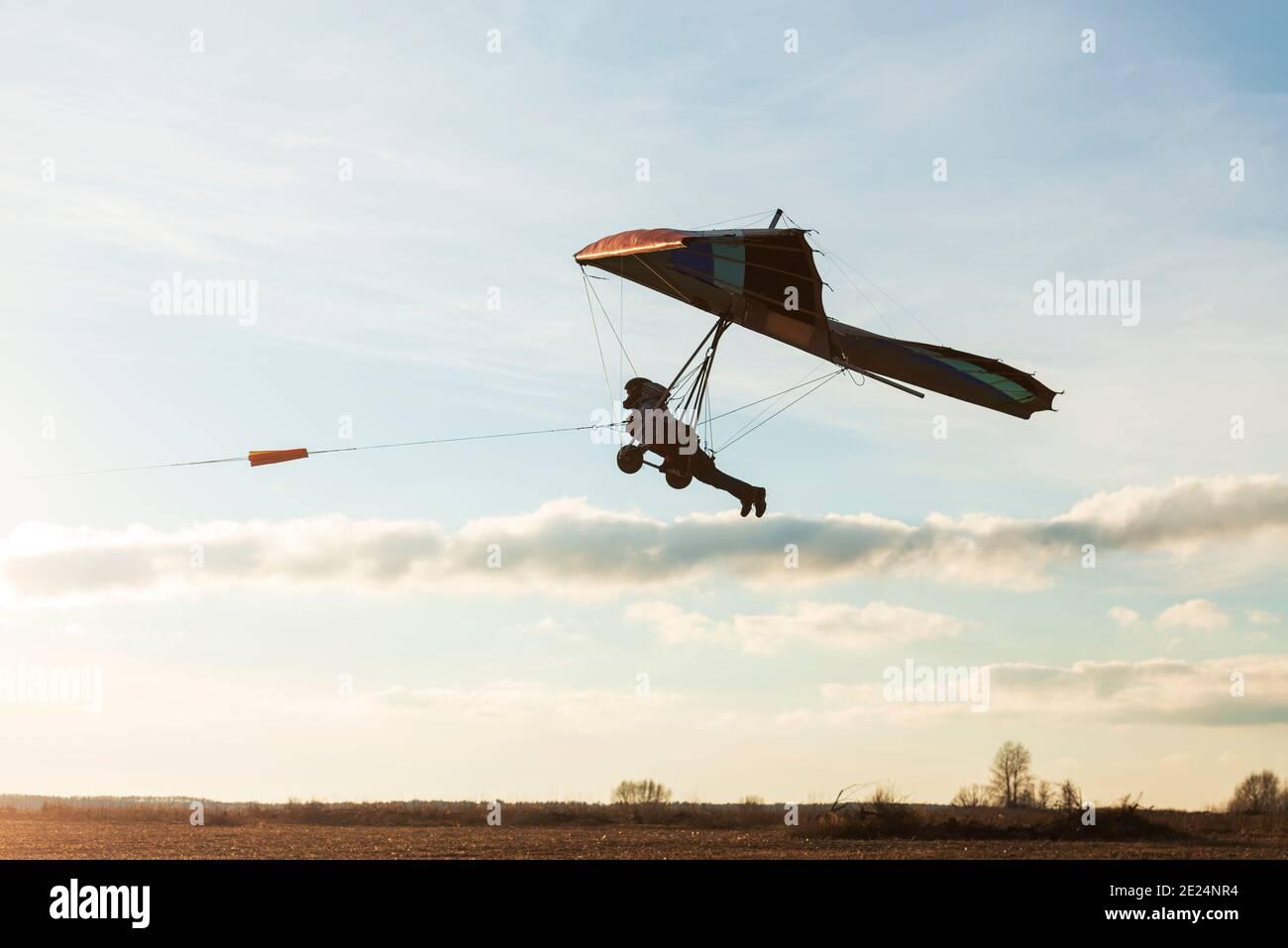 Beginner hang glider wing silhouette on the sunset sky Stock Photo