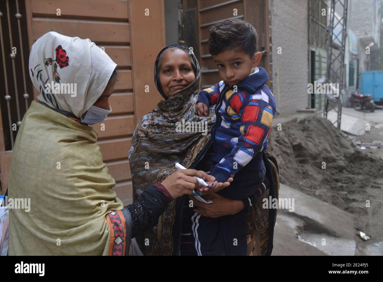 Pakistani healthcare worker administers a polio vaccine to a child during a polio vaccination door-to-door campaign in Lahore Stock Photo