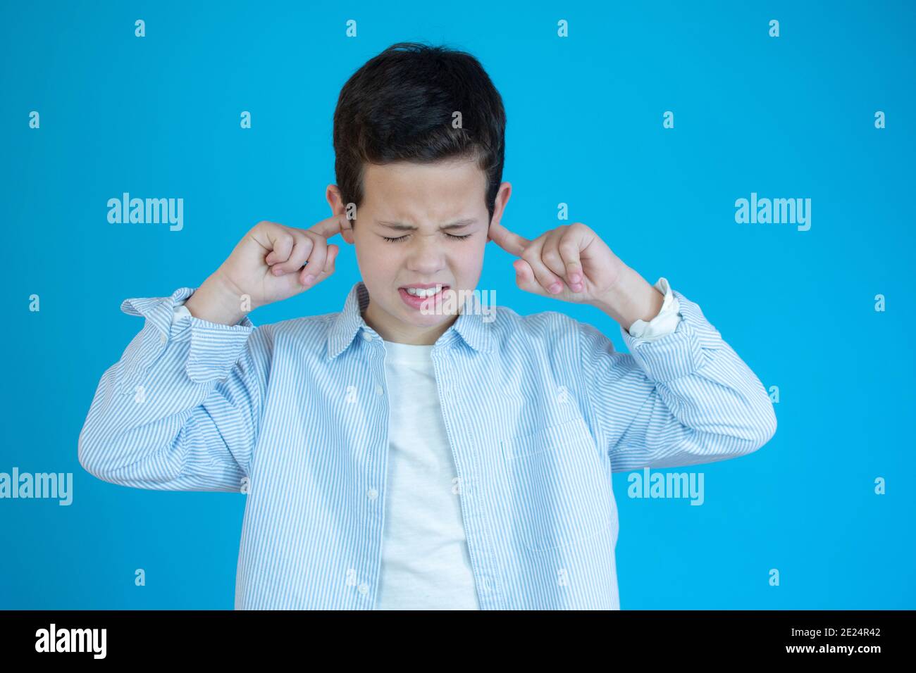 Boy covering his ears over blue background Stock Photo Alamy
