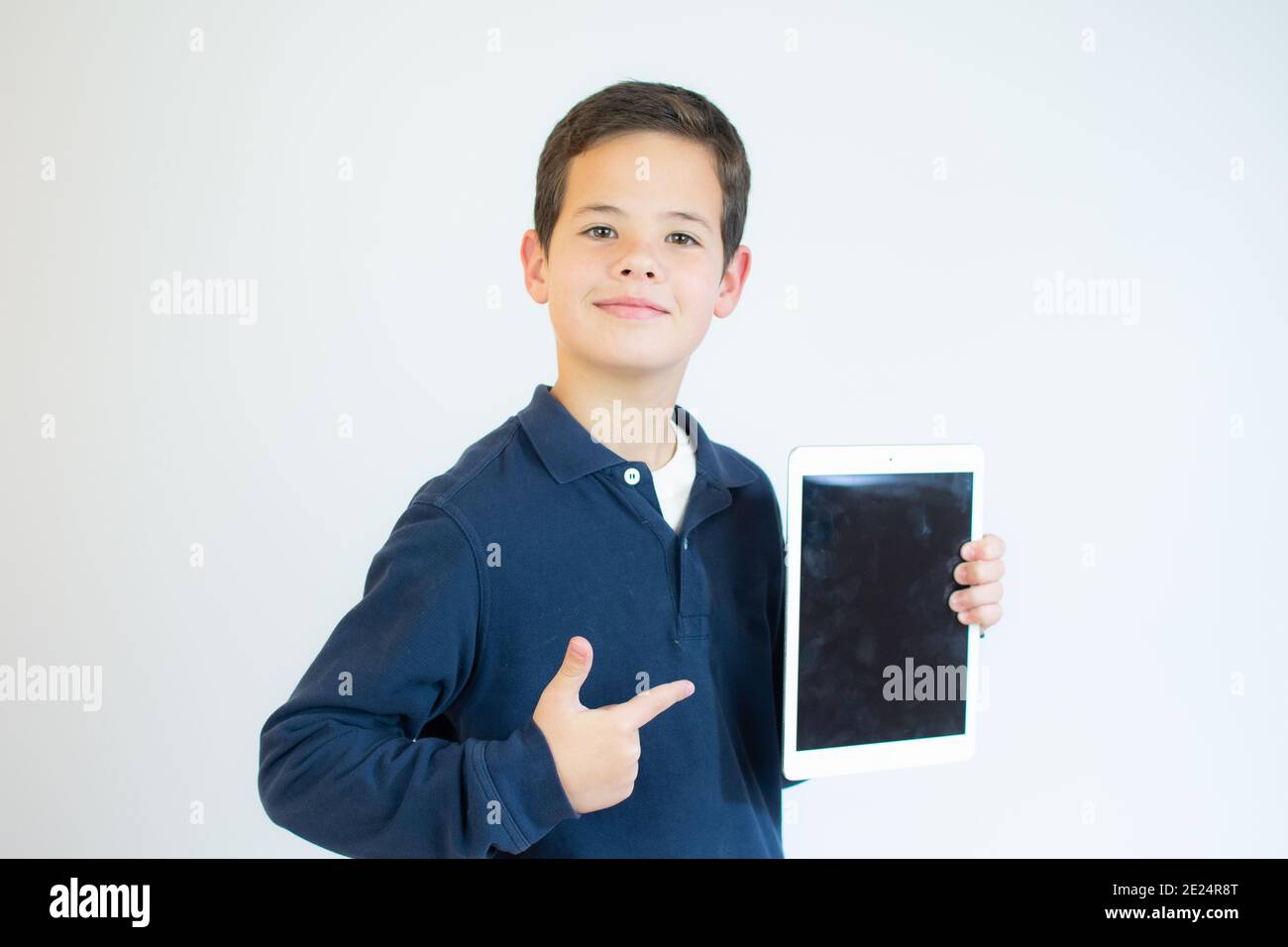 Portrait of a cute smiling boy using a tablet computer against a white ...