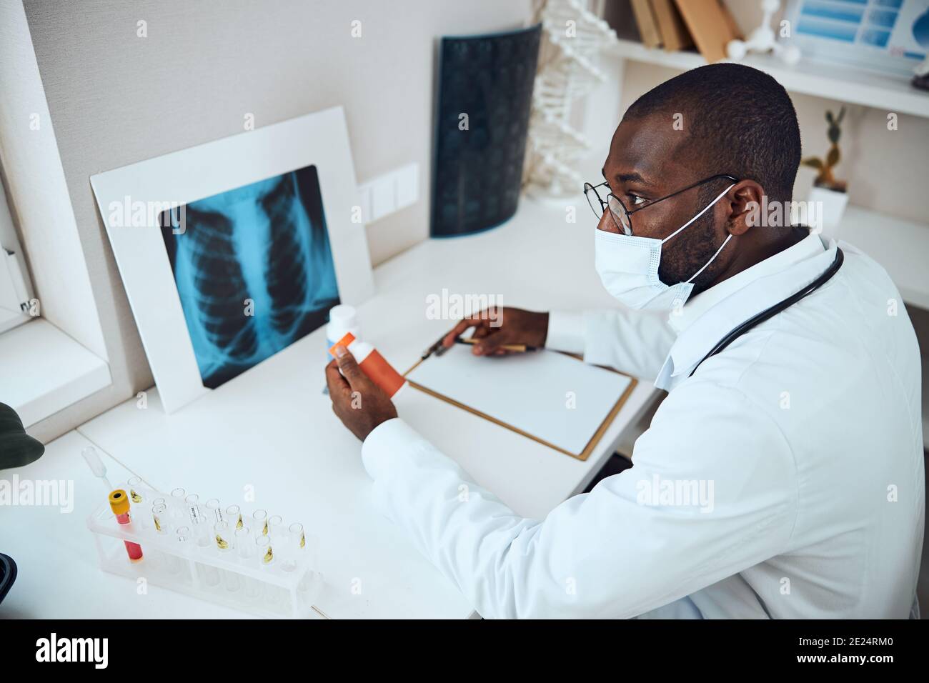 Hospital worker giving a serious look while holding pill bottle Stock