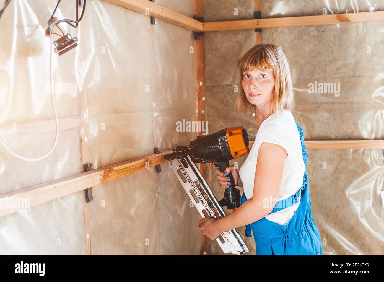 Woman builder in work overalls with drill and nail gun Stock Photo