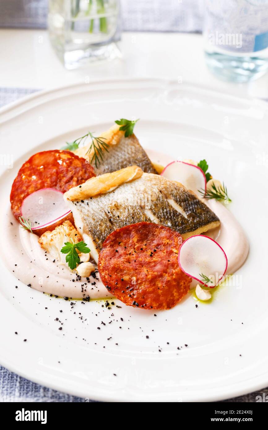 Pike perch fillet with chorizo, cauliflower and radish in a restaurant serving. Close up. Keto, paleo, fodmap diet food. Stock Photo