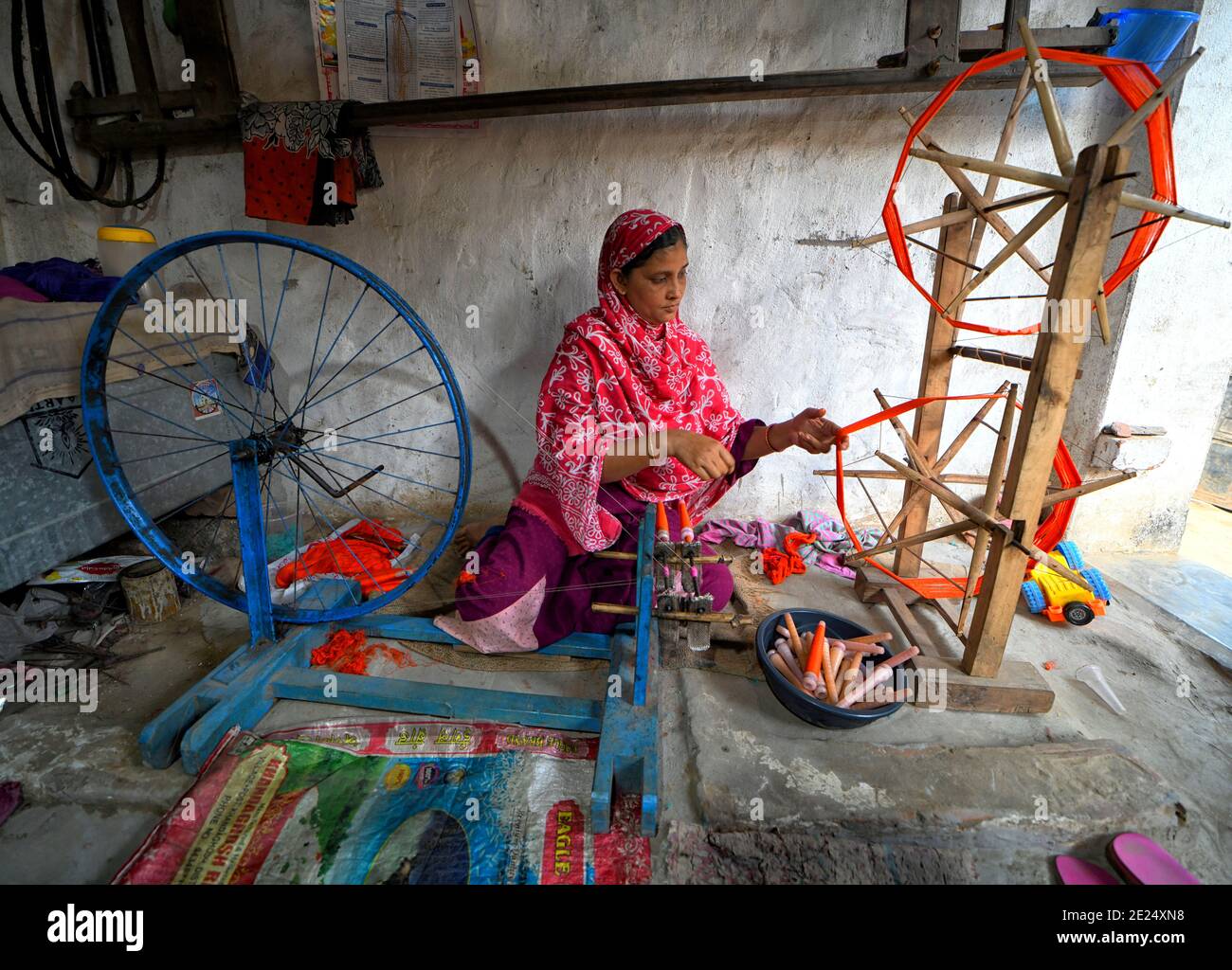 A woman seen extracting colourful yarns using a Handloom machine from the Jute threads.The traditional dress of an Indian Woman is Saree which is very popular throughout the World for its design, variety, textures, and colours. Santipur & Fulia from Nadia districts of West Bengal, India where 90 % population are engaged in weaving activities from long Generation. Stock Photo