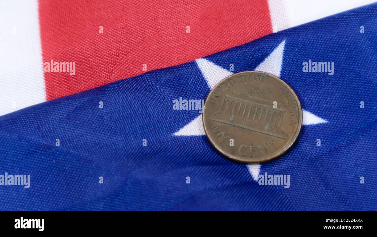 A 1 cent American dollar coin lies on the American flag. The currency is one cent over the flag of the United States Stock Photo
