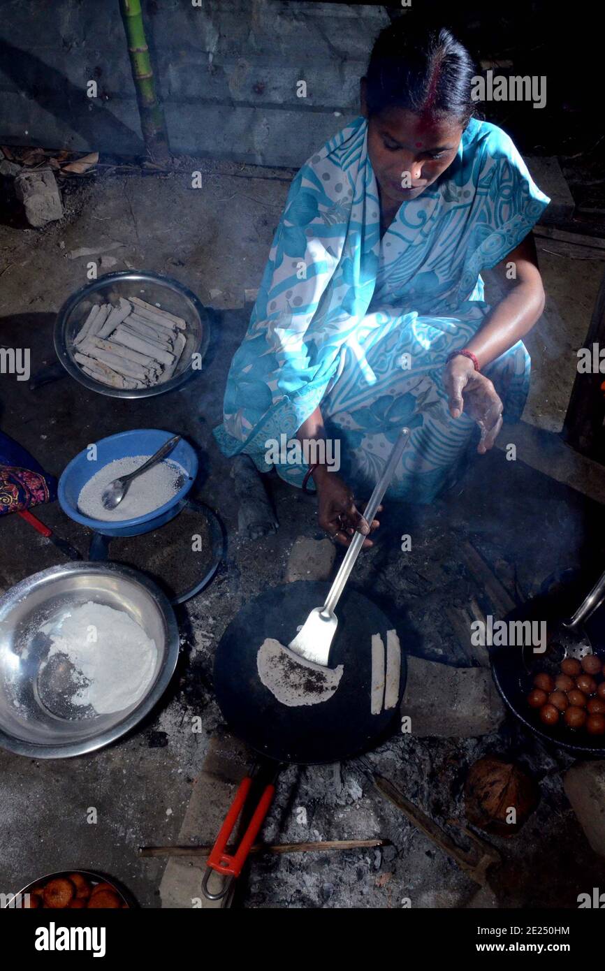 Nagaon, Assam, India - 12  January 2021: A lady preparing traditional teel pithas for Magh Bihu  in Kachamari village in Nagaon district of Assam, India. Magh Bihu in particular, is a celebration of the bounty of nature’s harvest, and an ode to the continuity of existence. It is only natural that Magh Bihu or Bhogali Bihu, as it is commonly called, is a rich celebration of the State’s rich reservoir of traditional food and delicacy preparations. Credit: DIGANTA TALUKDAR/Alamy Live News Stock Photo